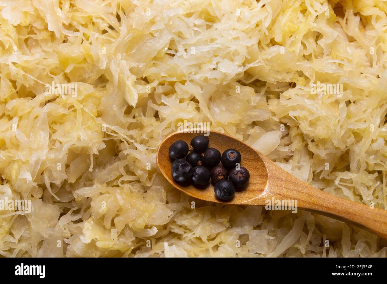 homemade raw sauerkraut with juniper berries on a small wooden spoon Stock Photo
