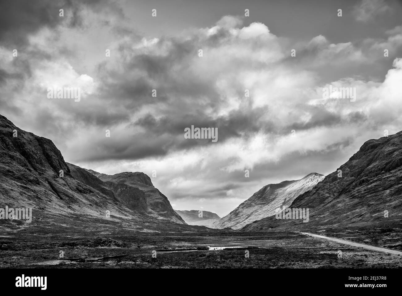 Stunning  black and white landscape image view down Glencoe Valley in Scottish Highlands with mountain ranges in dramatic Winter lighting Stock Photo