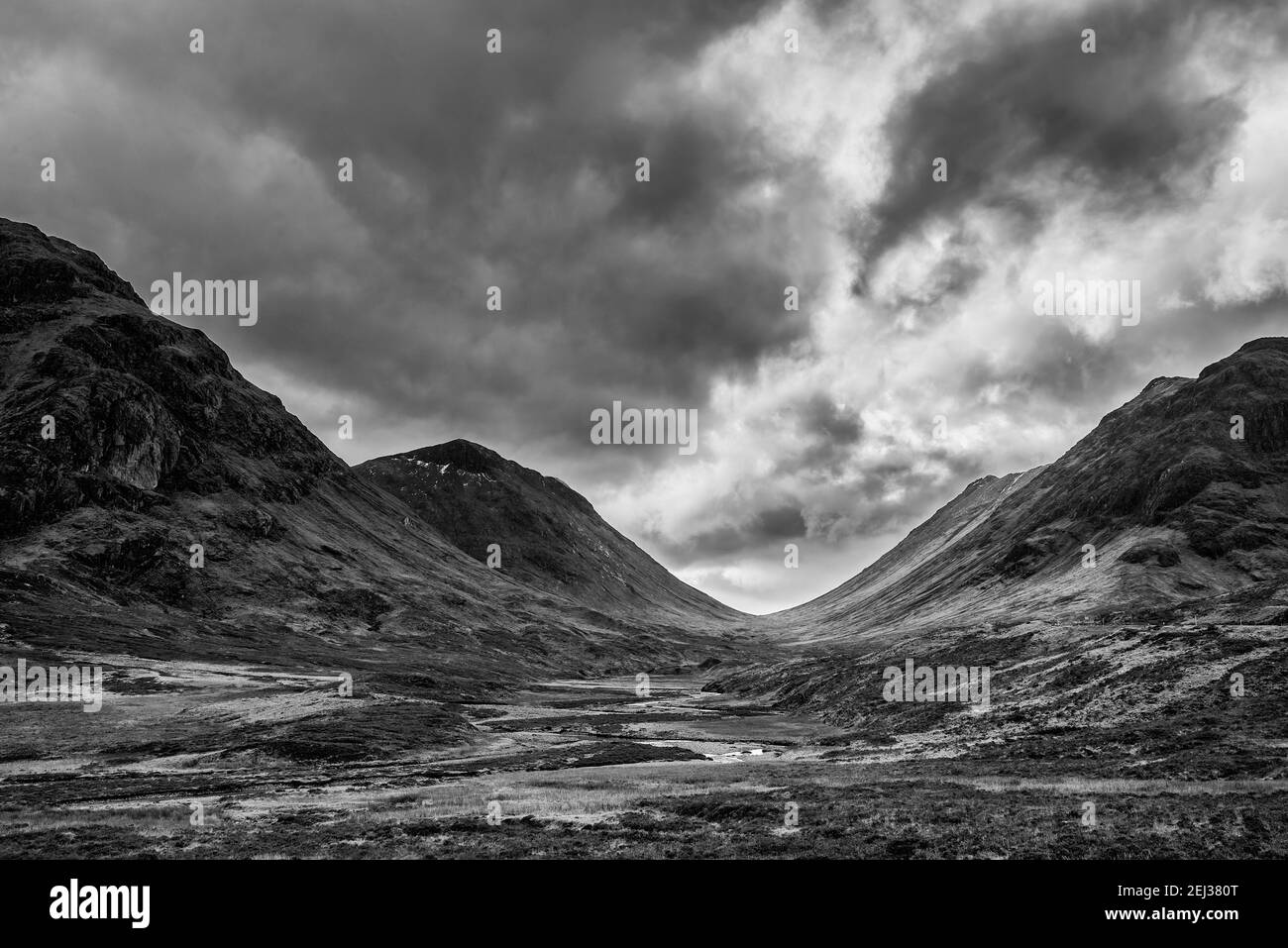 Stunning  black and white landscape image view down Glencoe Valley in Scottish Highlands with mountain ranges in dramatic Winter lighting Stock Photo