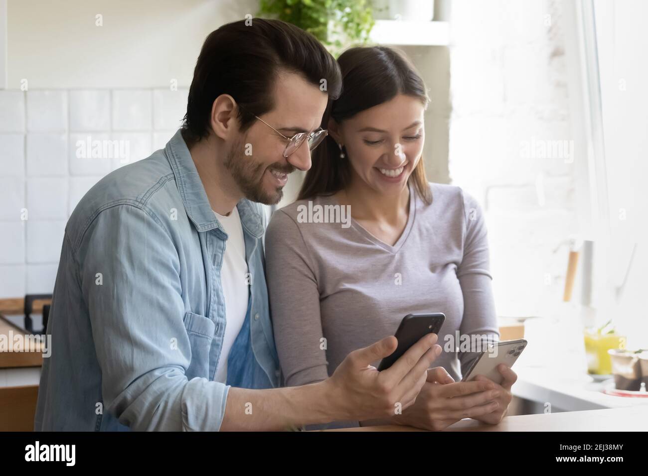 Overjoyed millennial couple have fun using cellphones Stock Photo