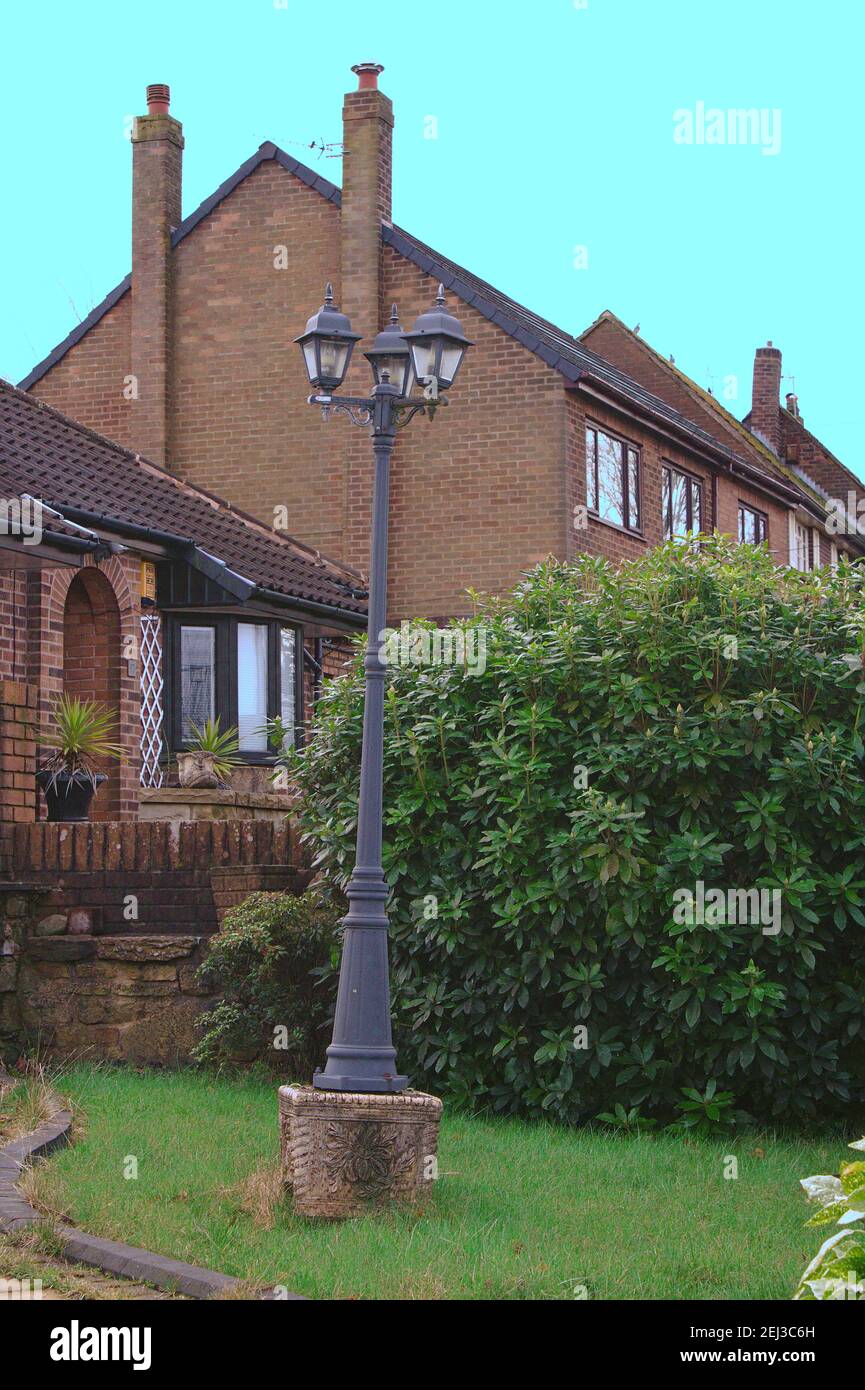 Concrete flower base with a victorian style lamp post fastened to it in a English garden Stock Photo