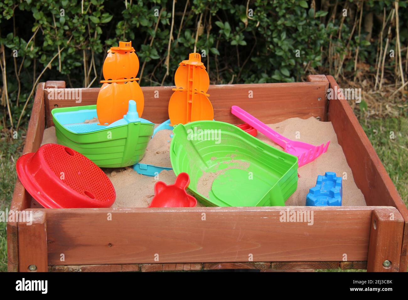 A Collection of Plastic Toys in a Garden Sandpit. Stock Photo