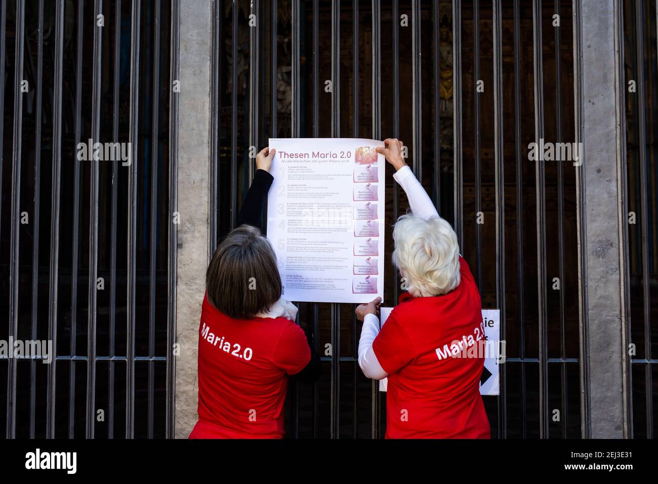 Freiburg, Germany. 21st Feb, 2021. Two activists of the Catholic reform  initiative Maria 2.0 hang a poster with their theses on the main portal of  the cathedral. The activists demand, among other
