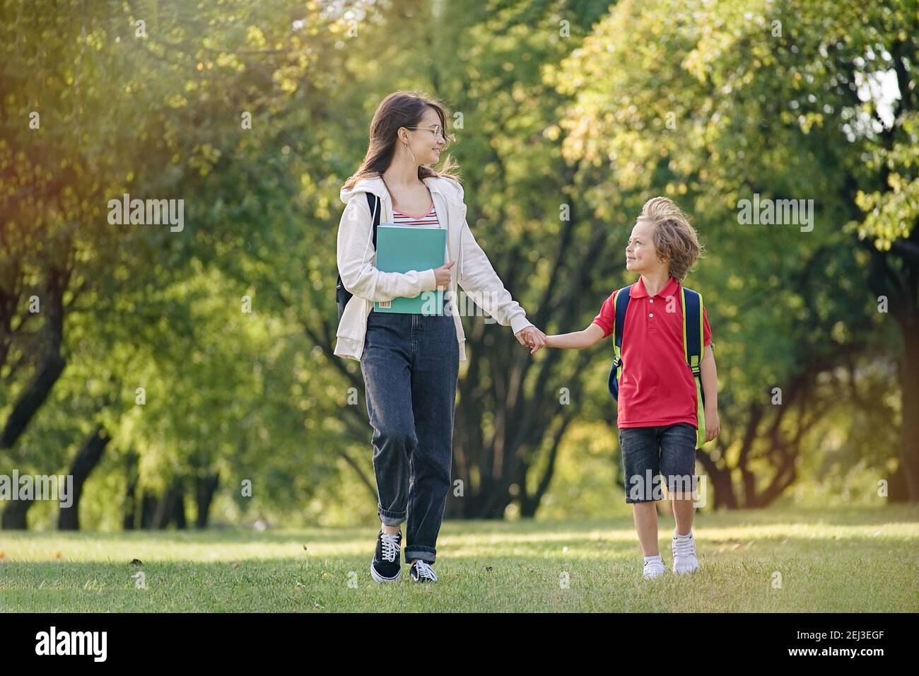 School Children return from school in a good mood. Brother and sister are walking along the park Stock Photo