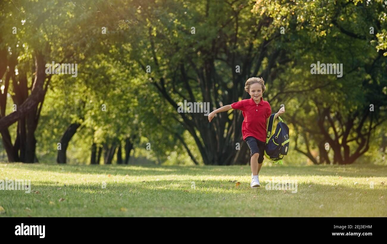 The schoolboy returns from school in a good mood. The boy runs in the park Stock Photo