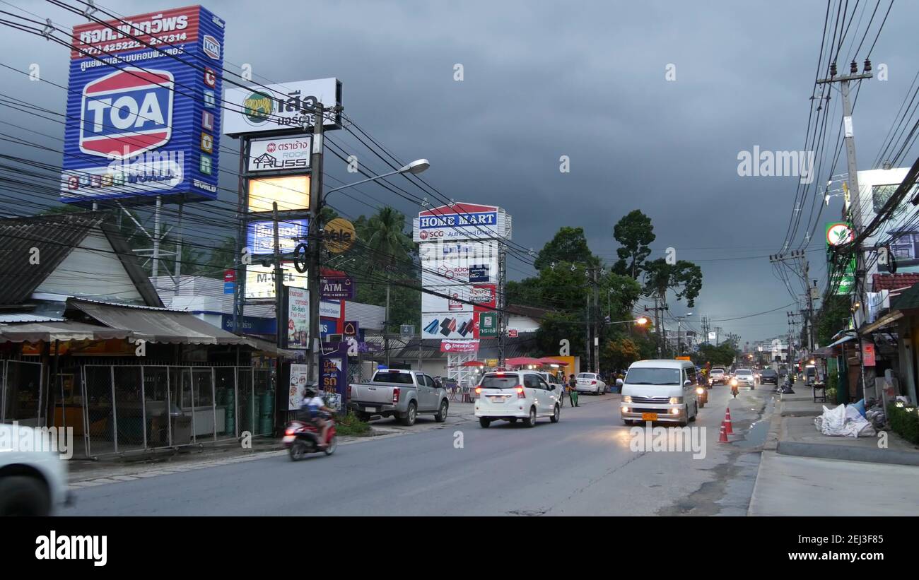KOH SAMUI ISLAND, THAILAND - 21 JUNE 2019 Busy transport populated city street in cloudy day. Typical street full of motorcycles and cars. Thick blue Stock Photo