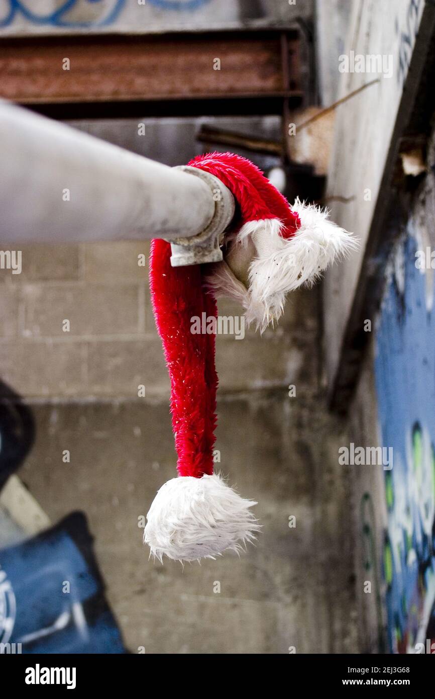 A discarded Santa Claus hat hanging on the pipe outside, end of winter holidays Stock Photo