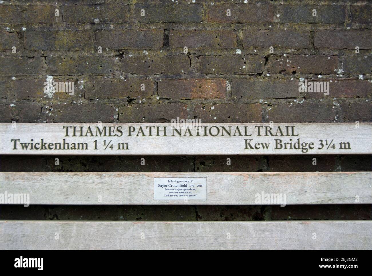 bench on the thames path national trail showing distances to twickenham and kew bridge, london, england, and with a memorial plaque Stock Photo