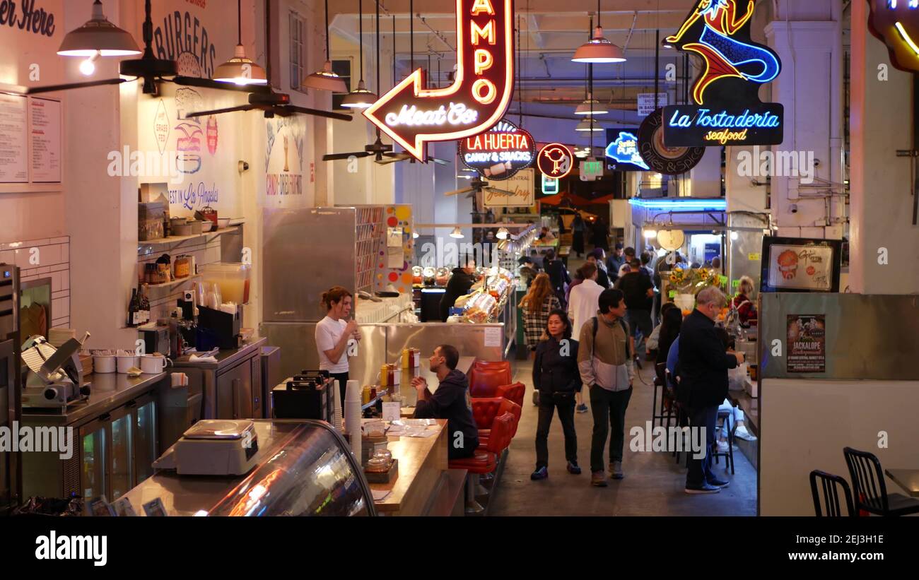 LOS ANGELES, CALIFORNIA, USA - 27 OCT 2019: Grand central market street lunch shops with diversity of glowing retro neon signs. Multiracial people on Stock Photo