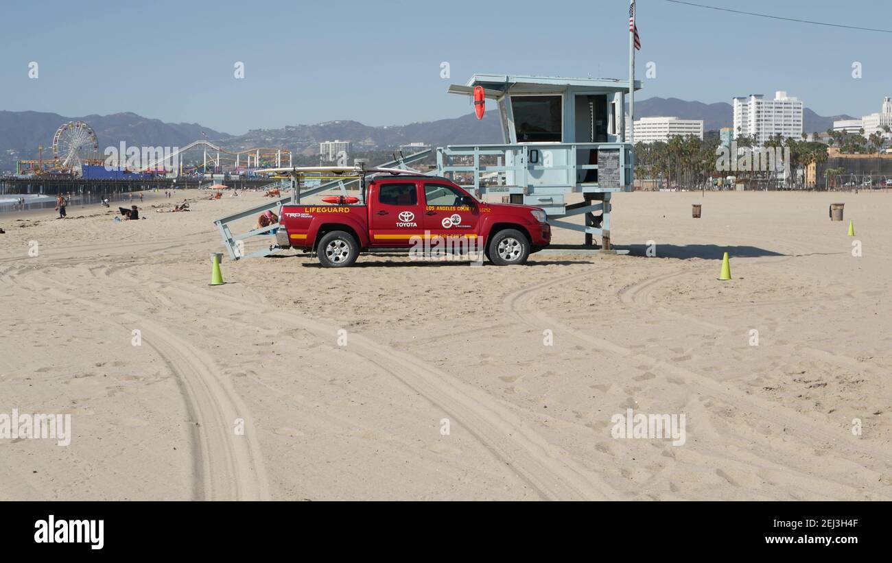 SANTA MONICA, LOS ANGELES CA USA - 28 OCT 2019: California summertime beach aesthetic. Iconic blue wooden watchtower, red lifeguard car on sandy sunny Stock Photo