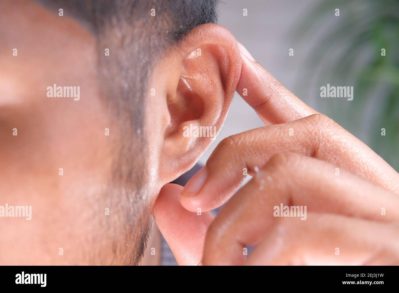 close up of young man holding ear suffering pain  Stock Photo