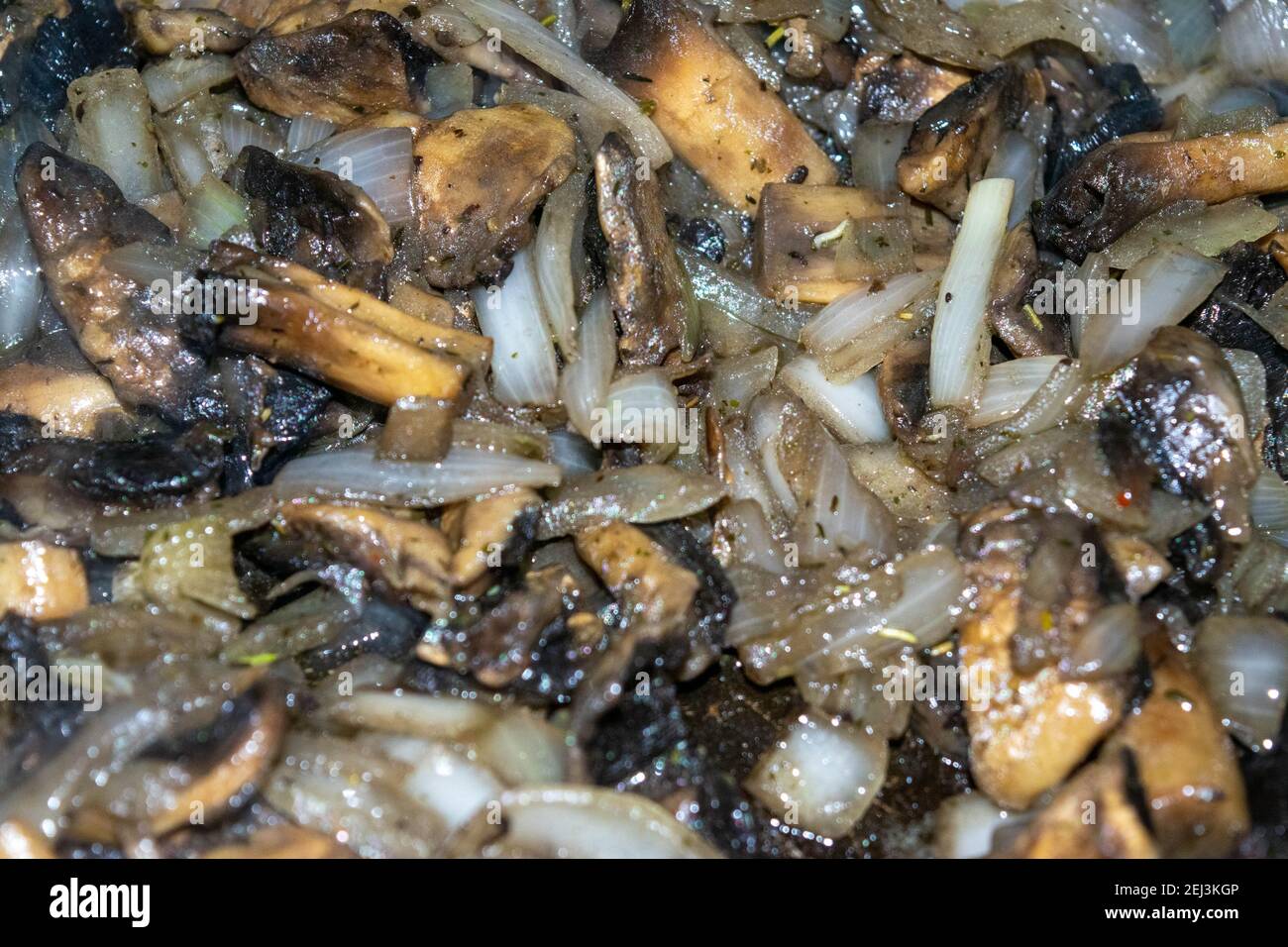 Wild mushrooms with onions are fried in a frying pan. Autumn harvest. Close-up, selective focus, surface texture. Stock Photo