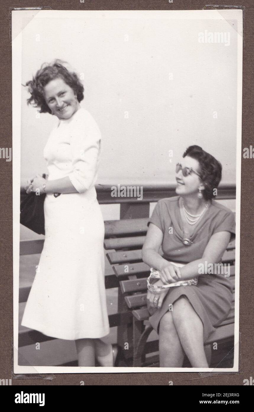 Vintage black and white photo of two women sat on a bench on holiday 1930s. Stock Photo