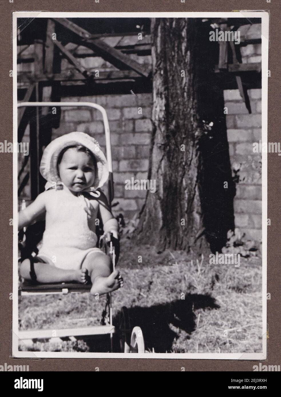 Vintage black and white photo of a young child in a buggy wearing a sunhat 1930s. Stock Photo