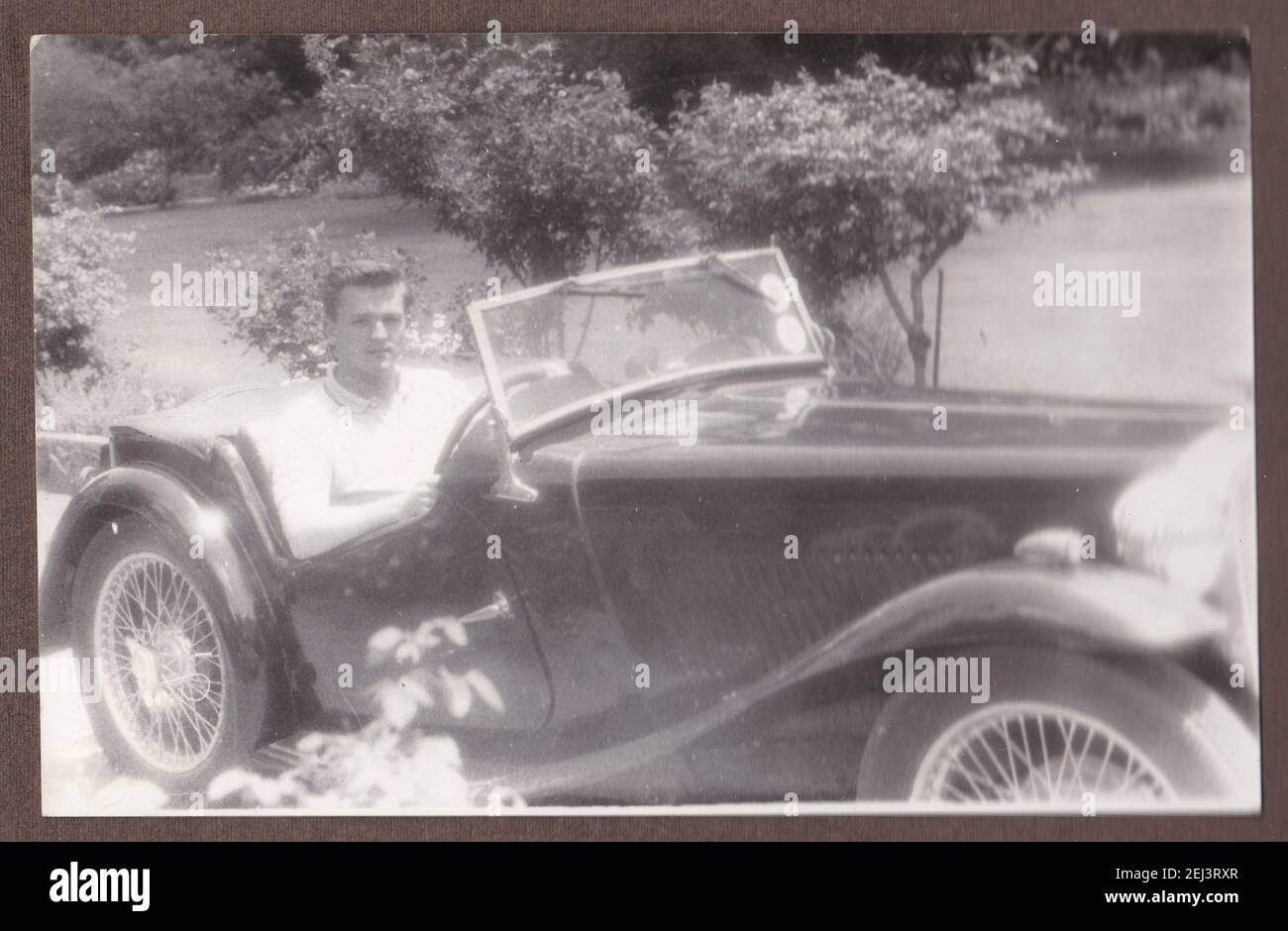 Vintage black and white photo of a young handsome man in a MGA car 1930s. Stock Photo