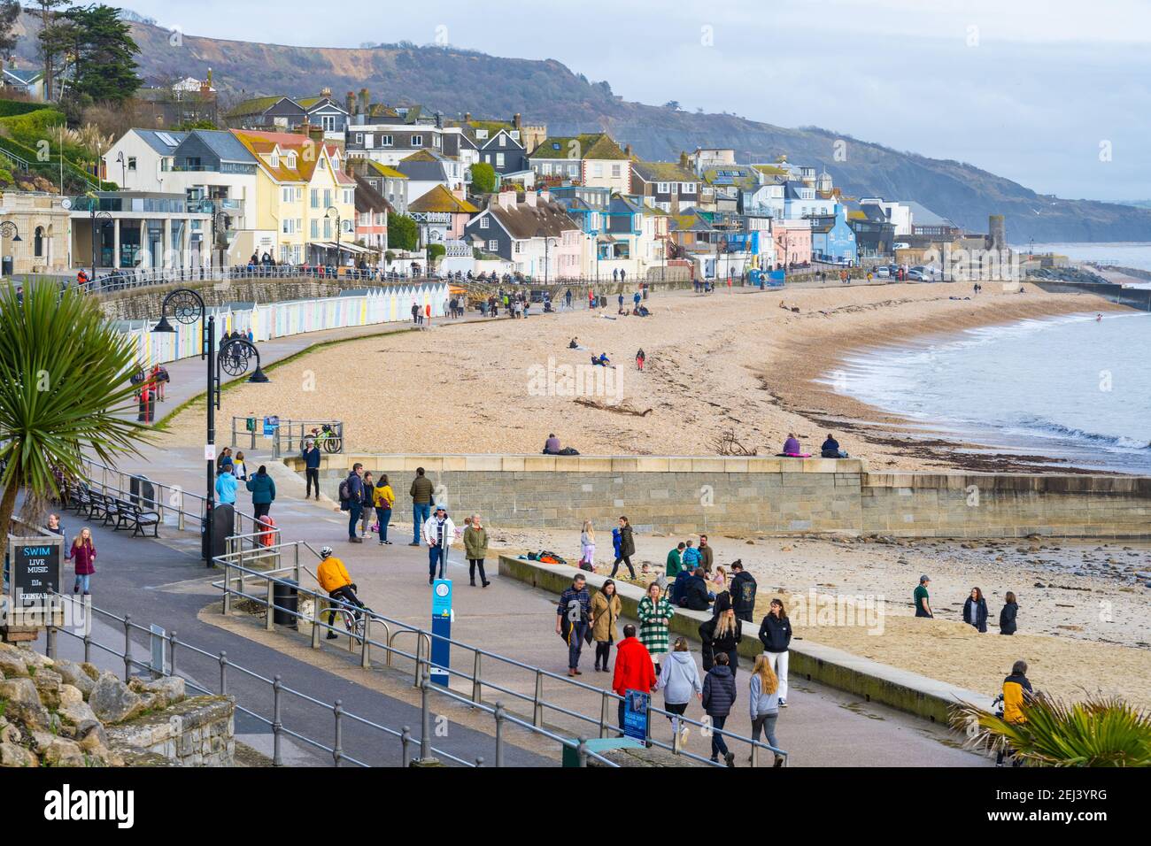 Lyme Regis, Dorset, UK. 21st Feb, 2021. UK Weather: People enjoy a warm and sunny Sunday afternoon on the beach at the seaside resort of Lyme Regis as the recent wet and gloomy weather clears bringing warmer, sunnier conditions next week. Credit: Celia McMahon/Alamy Live News Stock Photo