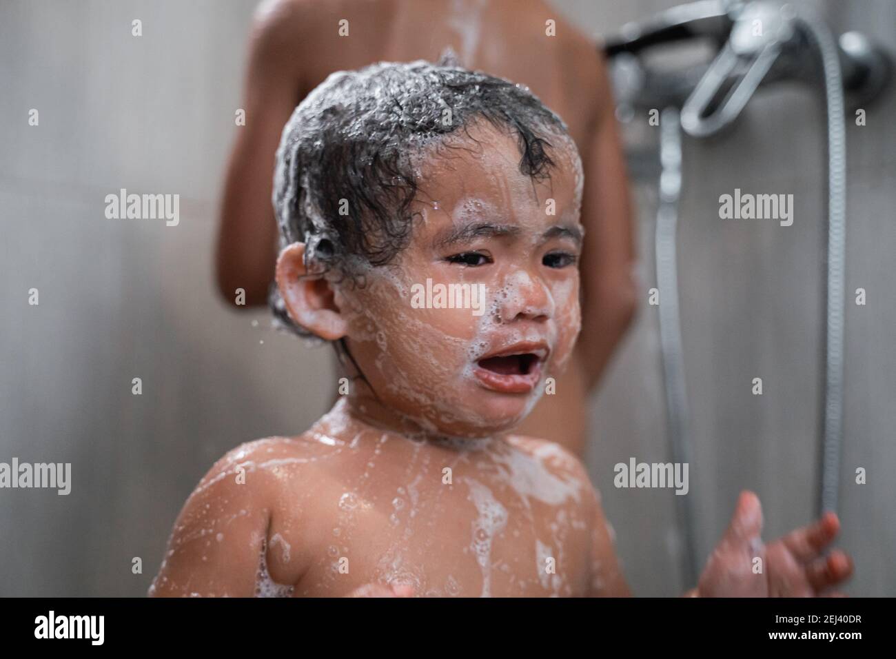 a baby crying with a face full of soap lather in the bathroom Stock