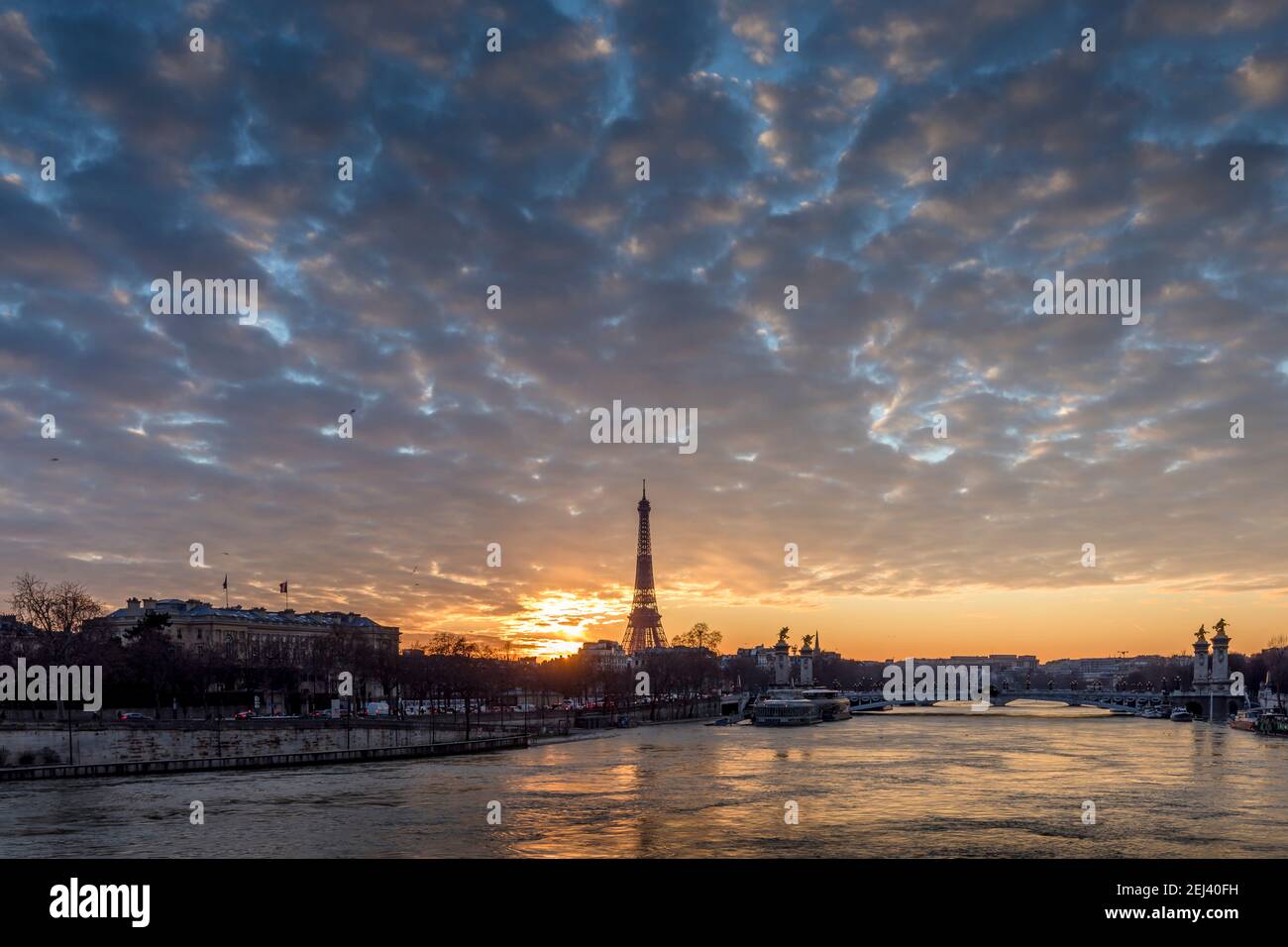 Paris, France - February 12, 2021: CItyscape of Paris in winter. Ships and brigde over Seine river with Eiffel tower in background and dramatic cloudy Stock Photo