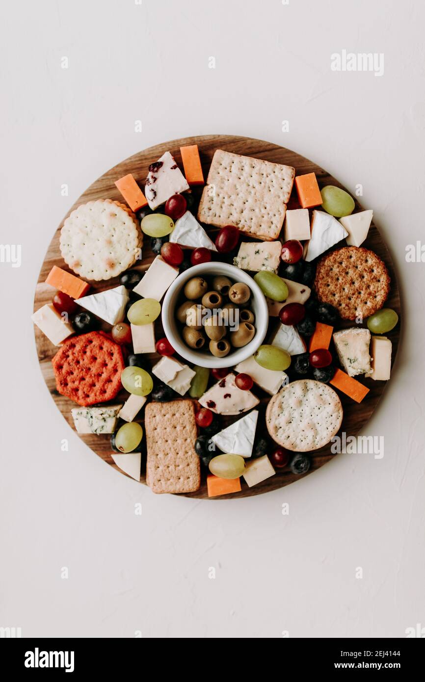 Cheese platter with different type of cheese. Camembert, cheddar, goat chesse, bleu, grapes and olive with crackers. Healthy vegetarian food idea. Stock Photo
