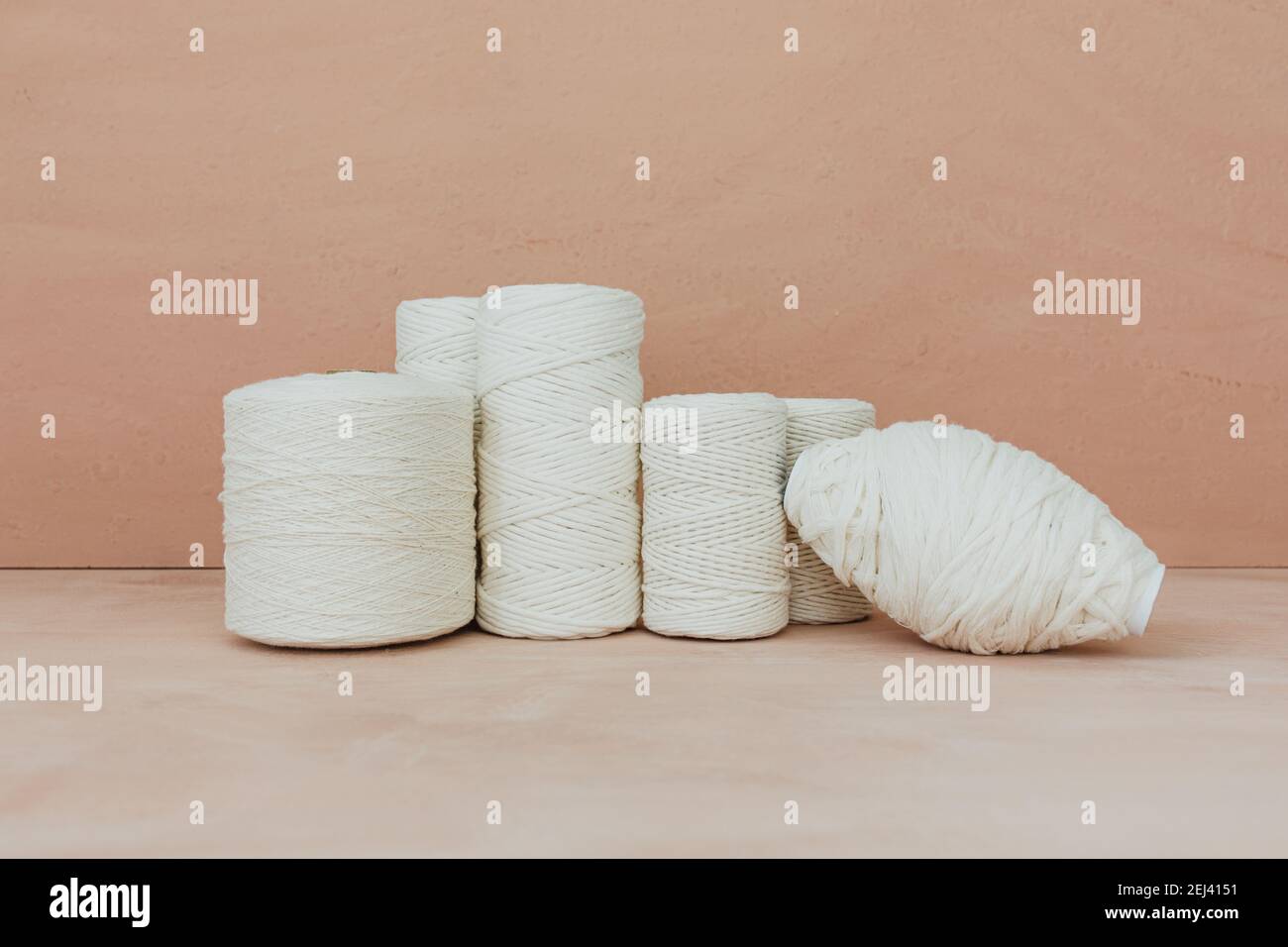 Set of white knitting yarn spool on beige background. Different size cotton threads. Stock Photo