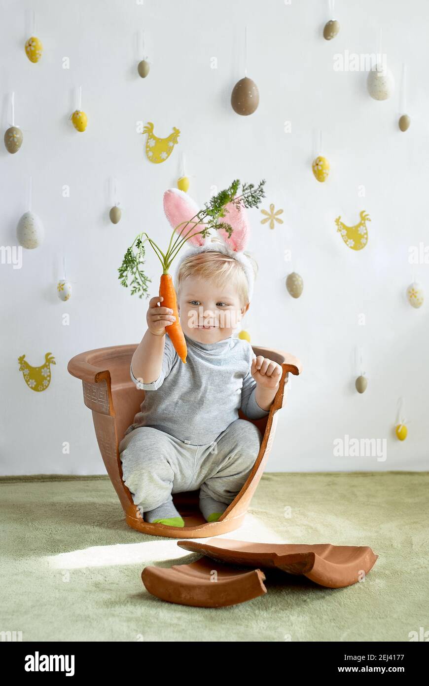 Cute young toddler boy in rabbit ears looking on a carrot Stock Photo