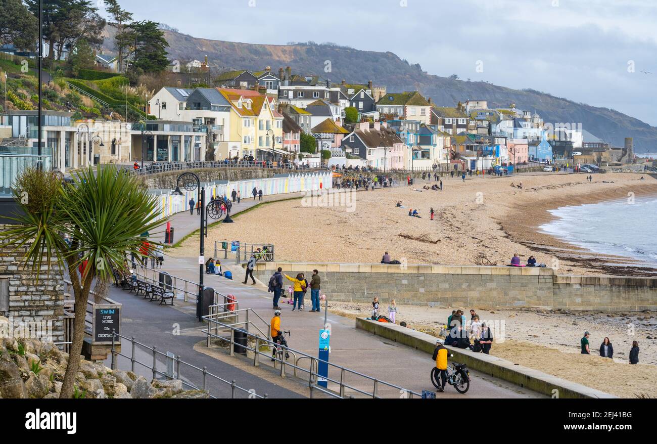 Lyme Regis, Dorset, UK. 21st Feb, 2021. UK Weather: People enjoy a warm and sunny Sunday afternoon on the beach at the seaside resort of Lyme Regis as the recent wet and gloomy weather clears bringing warmer, sunnier conditions next week. Credit: Celia McMahon/Alamy Live News Stock Photo