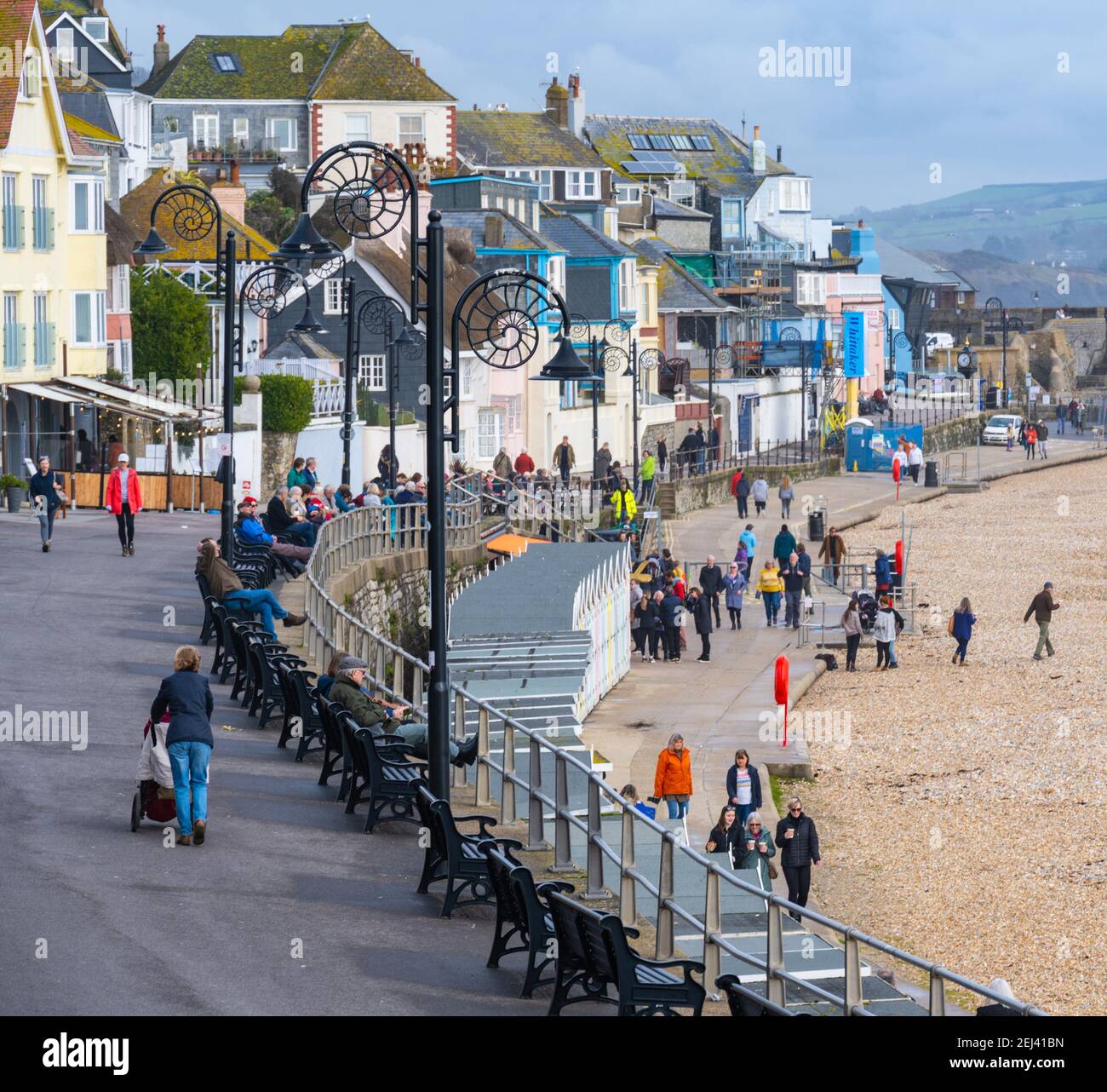 Lyme Regis, Dorset, UK. 21st Feb, 2021. UK Weather: People enjoy a warm and sunny Sunday afternoon on the beach at the seaside resort of Lyme Regis as the recent wet and gloomy weather clears bringing warmer, sunnier conditions next week. Credit: Celia McMahon/Alamy Live News Stock Photo