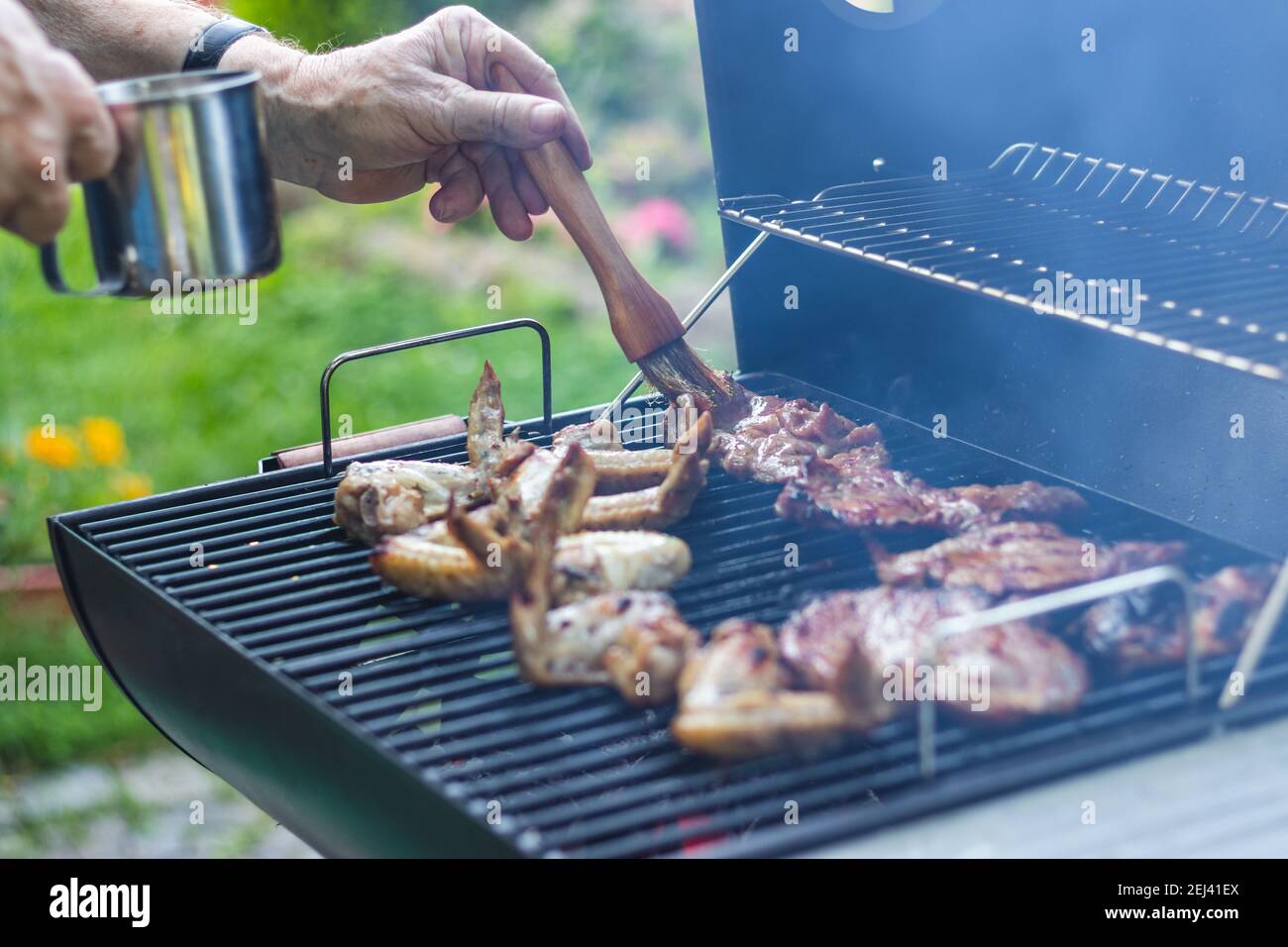 https://c8.alamy.com/comp/2EJ41EX/marinated-meat-on-grill-during-garden-party-summer-barbecue-outdoors-man-with-basting-brush-marinate-grilled-food-2EJ41EX.jpg