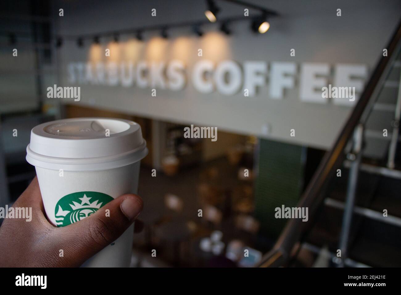 Starbucks cafe interior. A black man takes a coffee. Starbucks