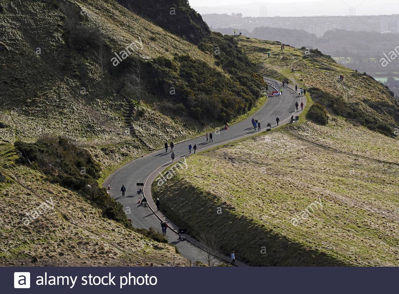 Edinburgh, Scotland, UK. 21st Feb 2021. People enjoying the sun and outdoors in Holyrood Park. People walking on Queens Drive. Credit: Craig Brown/Alamy Live News Stock Photo