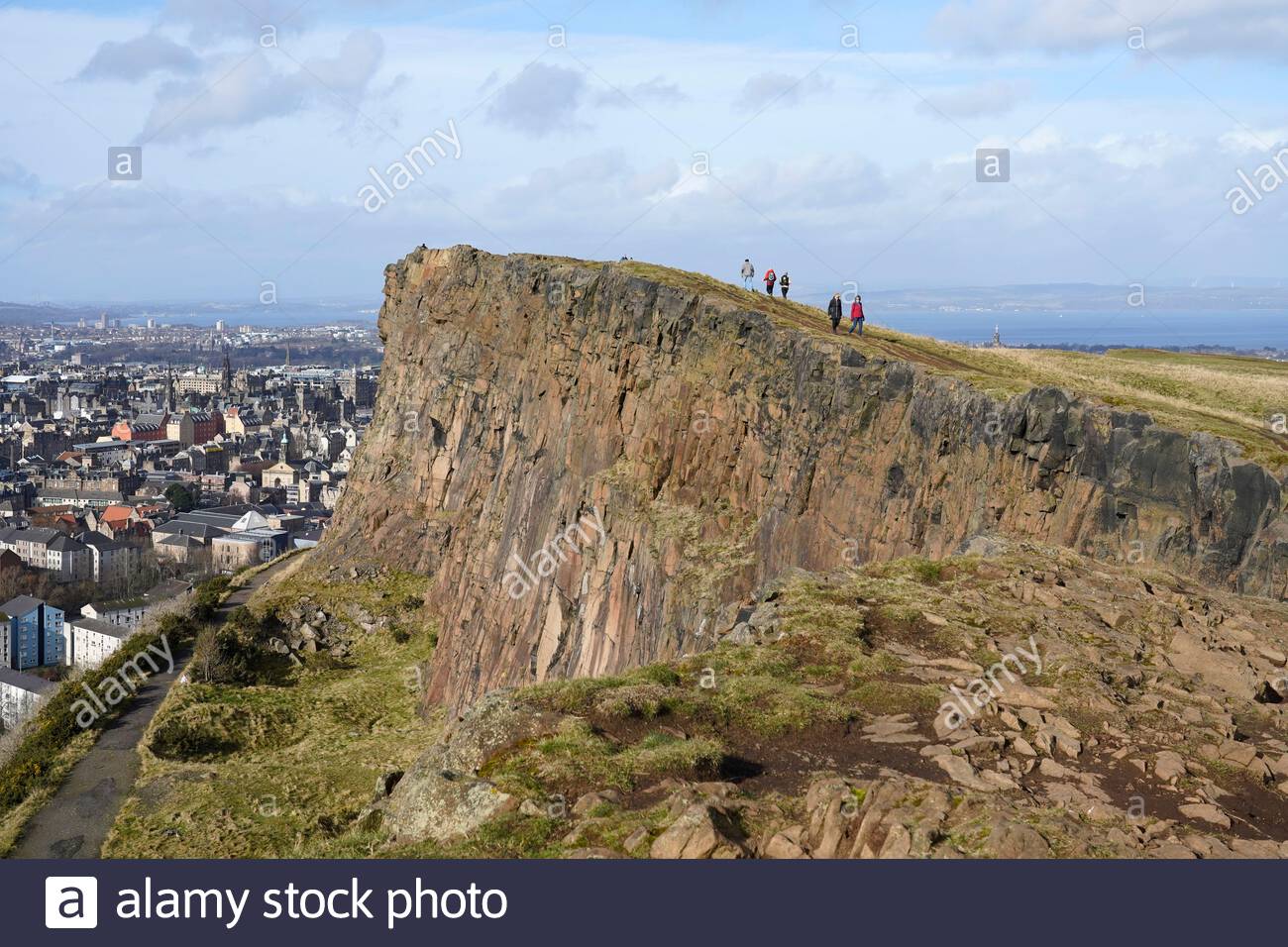 Edinburgh, Scotland, UK. 21st Feb 2021. People enjoying the sun and outdoors in Holyrood Park.  Walking along Salisbury Crags. Credit: Craig Brown/Alamy Live News Stock Photo