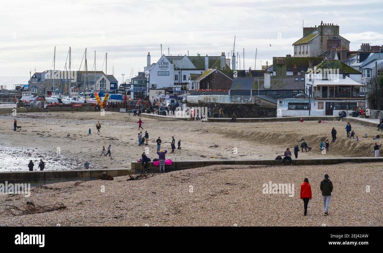 Lyme Regis, Dorset, UK. 21st Feb, 2021. UK Weather: People enjoy a warm and sunny Sunday afternoon on the beach at the seaside resort of Lyme Regis as the recent wet and gloomy weather clears bringing warmer, sunnier conditions next week. Credit: Celia McMahon/Alamy Live News Stock Photo