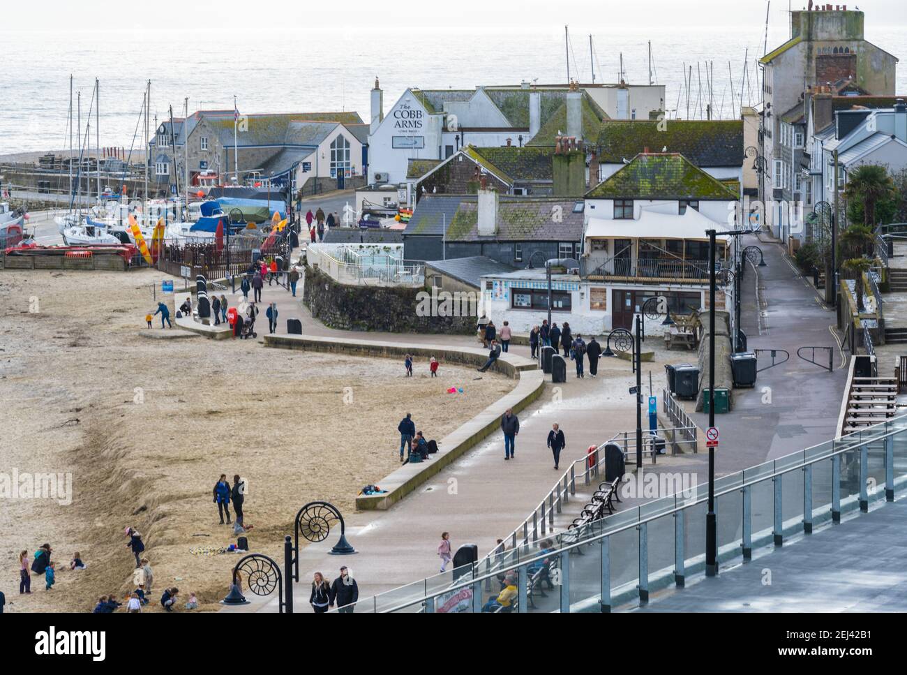 Lyme Regis, Dorset, UK. 21st Feb, 2021. UK Weather: People enjoy a warm and sunny Sunday afternoon on the beach at the seaside resort of Lyme Regis as the recent wet and gloomy weather clears bringing warmer, sunnier conditions next week. Credit: Celia McMahon/Alamy Live News Stock Photo