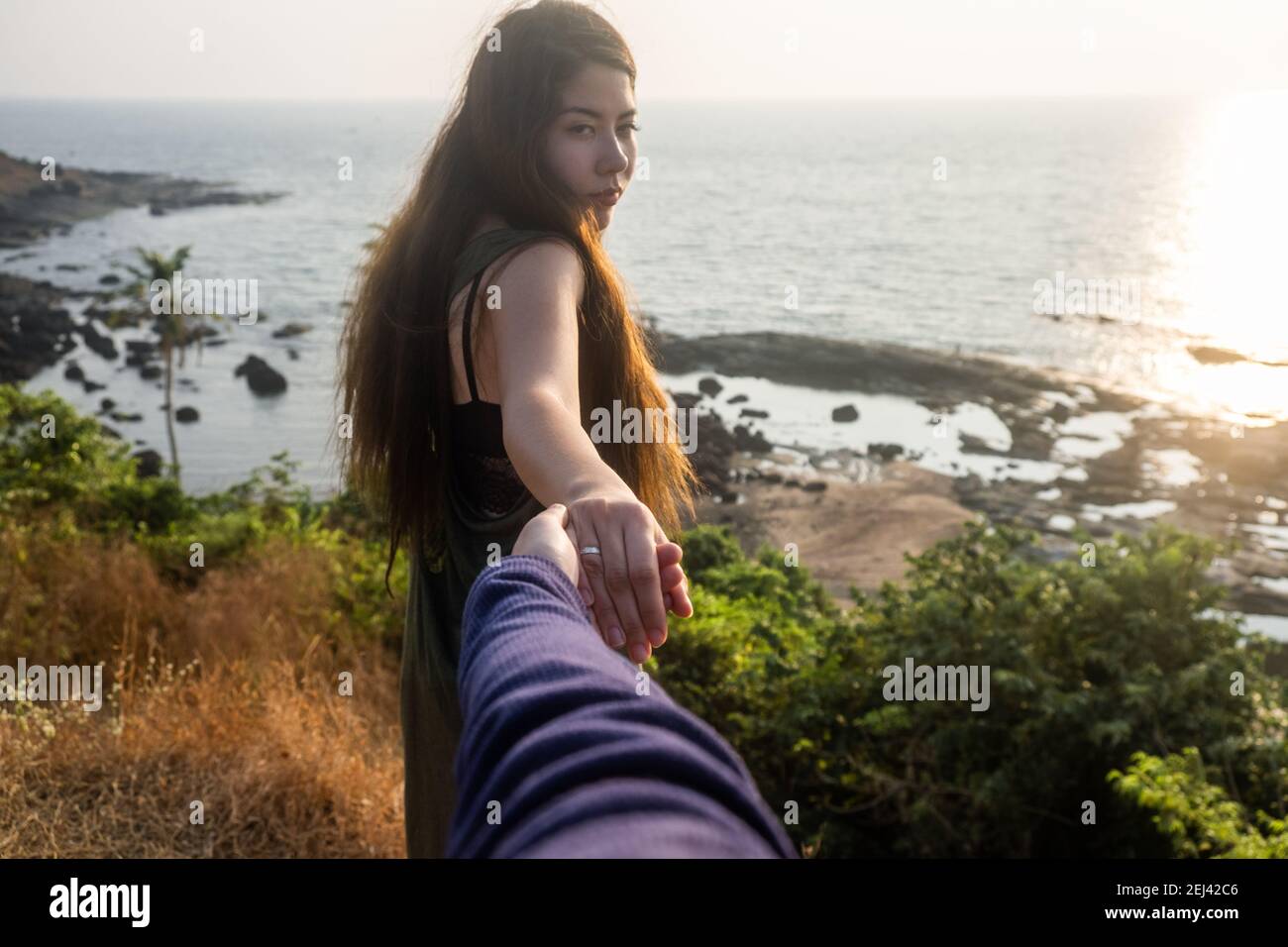 Shot of a young woman leading someone by the hand at the beach Stock Photo