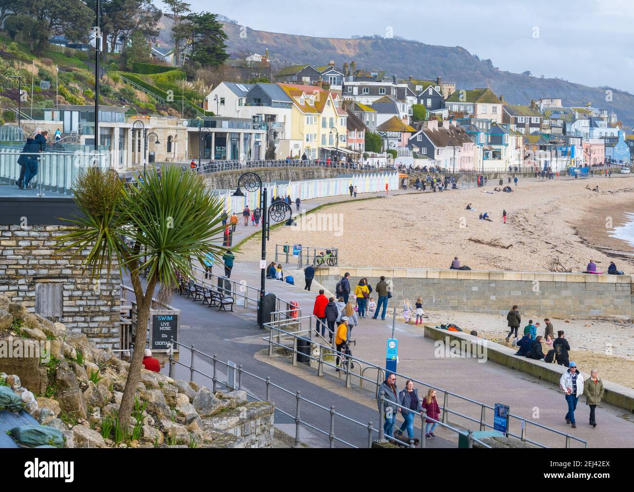 Lyme Regis, Dorset, UK. 21st Feb, 2021. UK Weather: People enjoy a warm and sunny Sunday afternoon on the beach at the seaside resort of Lyme Regis as the recent wet and gloomy weather clears bringing warmer, sunnier conditions next week. Credit: Celia McMahon/Alamy Live News Stock Photo