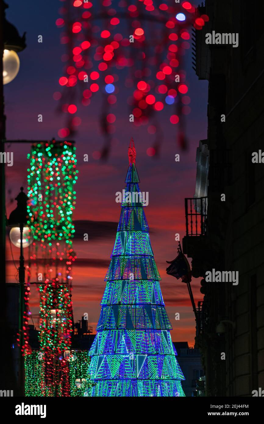Illuminated Christmas tree rising in the center of the Puerta del Sol square in Madrid at dusk. Stock Photo