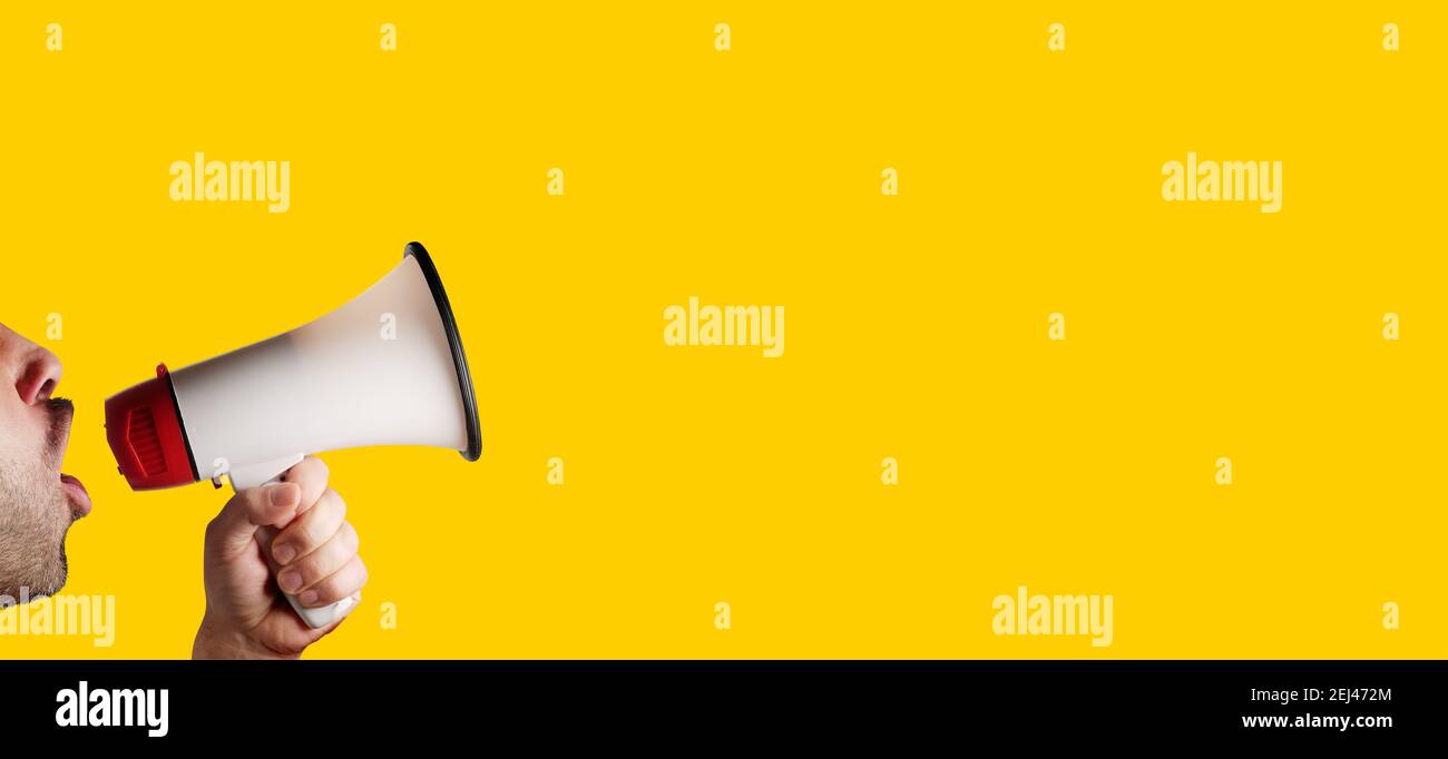 megaphone speaking announcing against isolated on yellow solid background Stock Photo