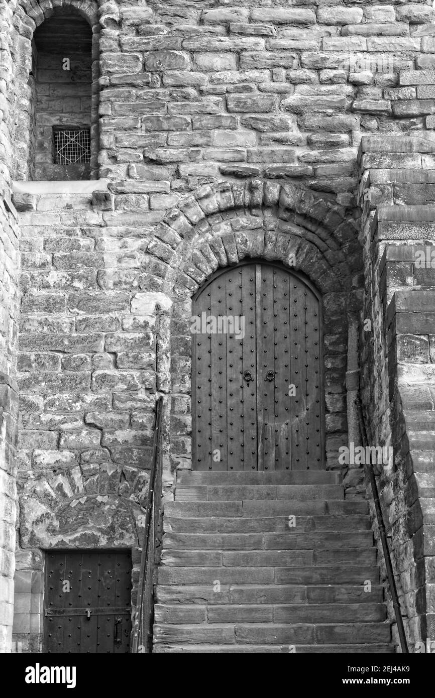 Steps lead up to a very old wooden door on the side of the historic Castle Keep in Newcastle, Tyne and Wear, Presented in black and white. Stock Photo
