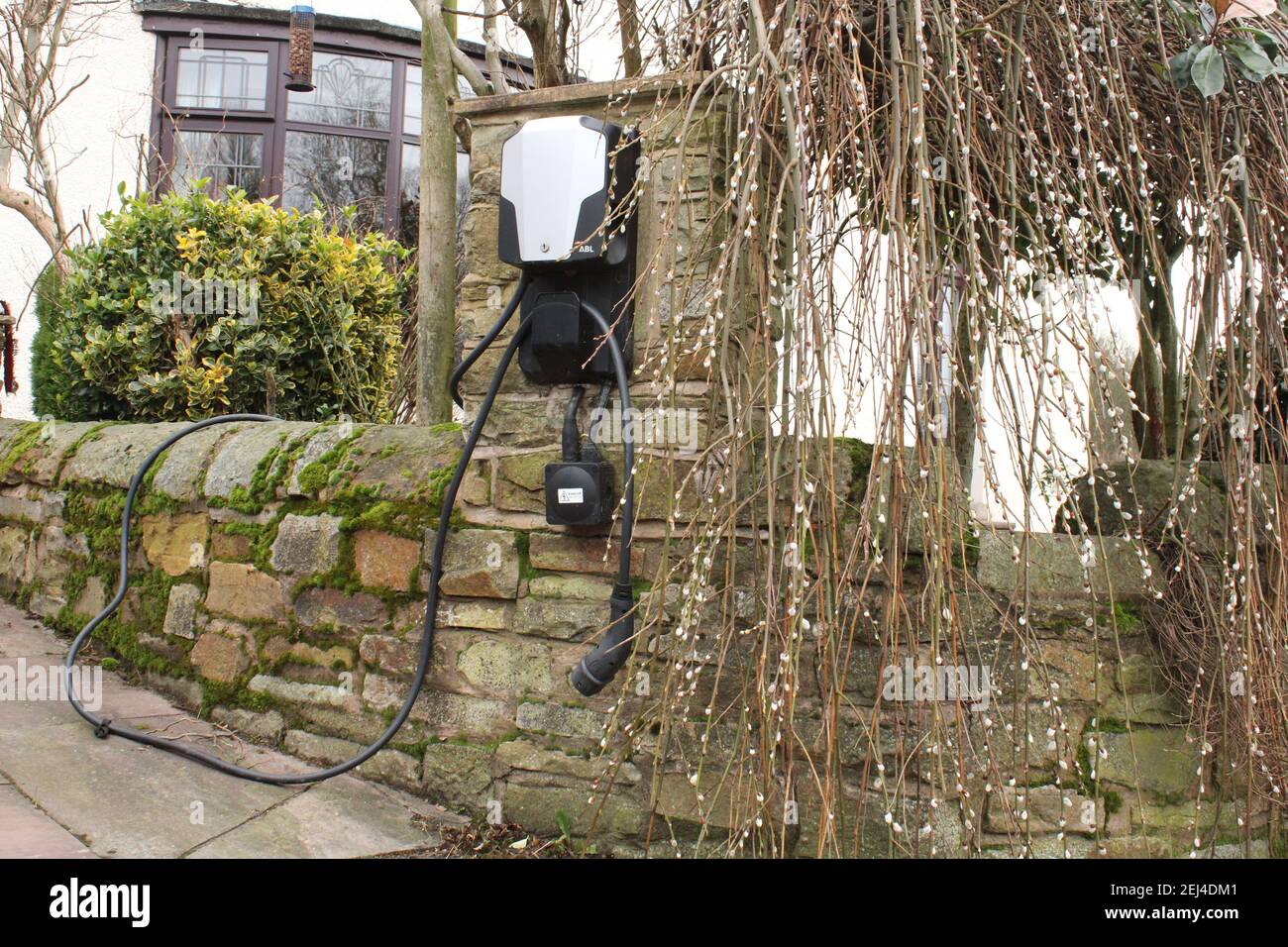Domestic electric charging point on a stone wall, electric car charging equipment UK Stock Photo