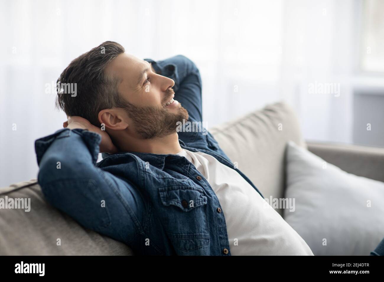 Handsome middle-aged man relaxing on sofa at home Stock Photo