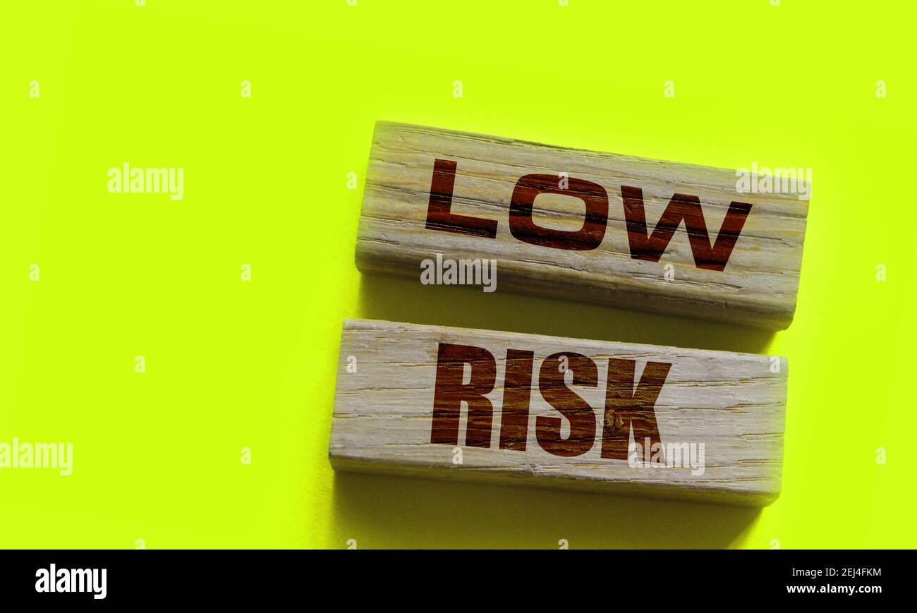 Low risk words wooden blocks on yellow. Business investment risks ...