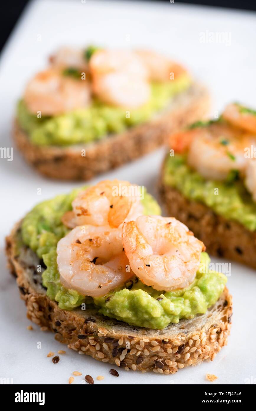 Toast with avocado and shrimps on multigrain bread. Healthy shrimp avocado appetizer Stock Photo