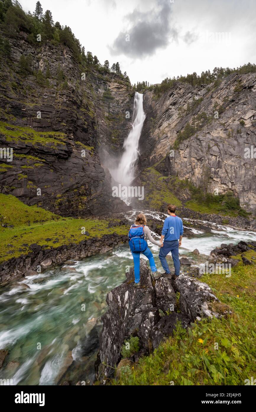 Two hikers, couple, standing on rocks by river Driva, Svoufallet waterfall, Amotan gorge, Gjora, Norway Stock Photo