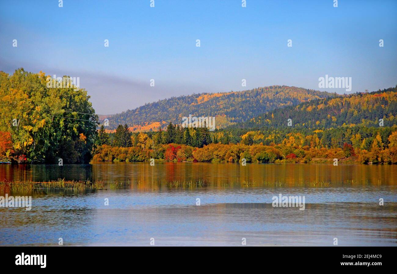 Amazing landscape of colorful wooded mountains and the water face of a wide river in autumn. Stock Photo