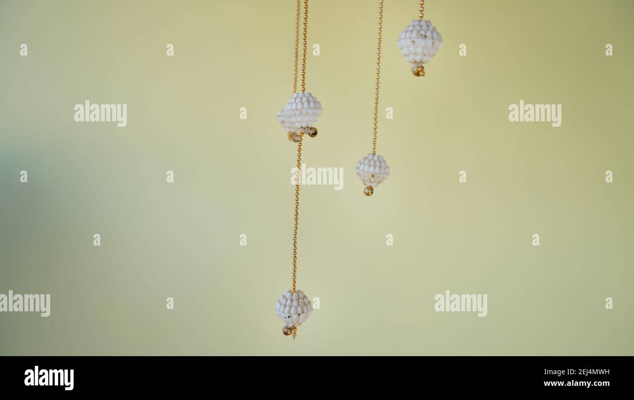 Wind chimes hanging in a room for decoration. White wind chimes with diamonds and golden chain isolated on white background Stock Photo