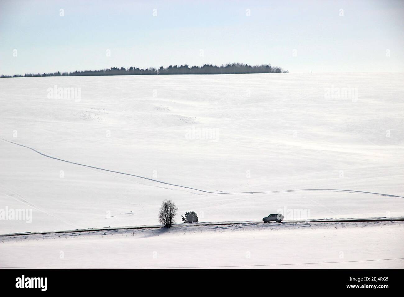 Black and white winter landscape of car on the road under the mountain slope. Stock Photo
