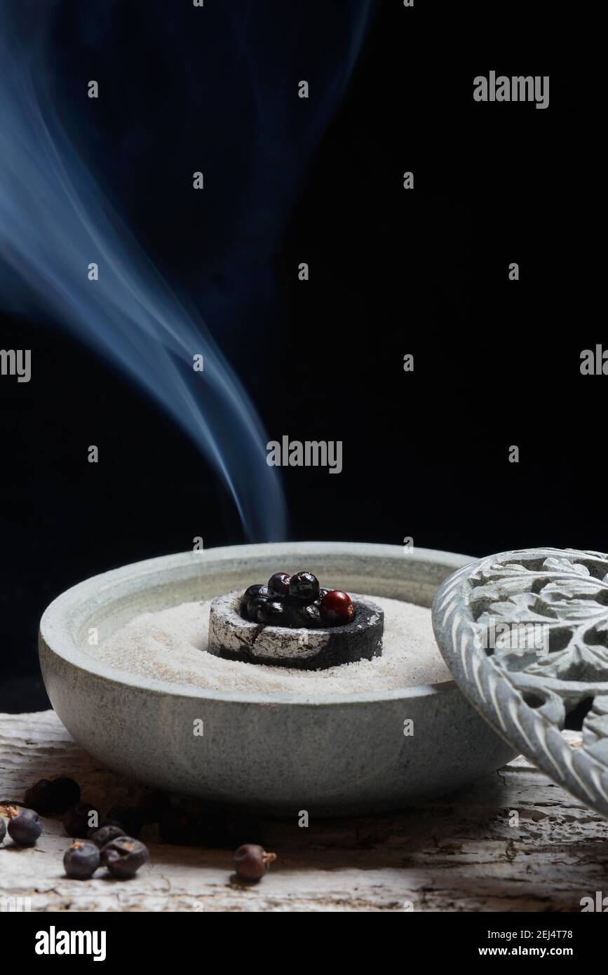 Burning juniper berries ( Juniperus communis) in shell with sand Stock