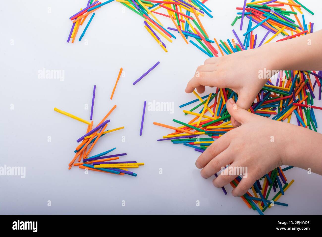 Kid playing with coloured wooden sticks for creativity on white ...