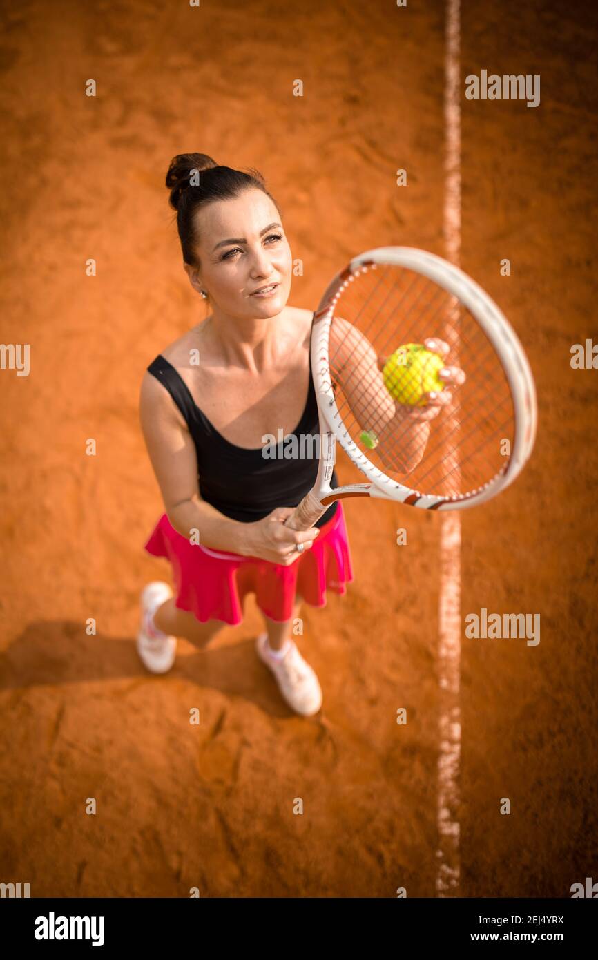 Top view of attractive young woman tennis player serving on a clay tennis  court. Interesting POV shot - sporty girl during tennis training in the clu  Stock Photo - Alamy