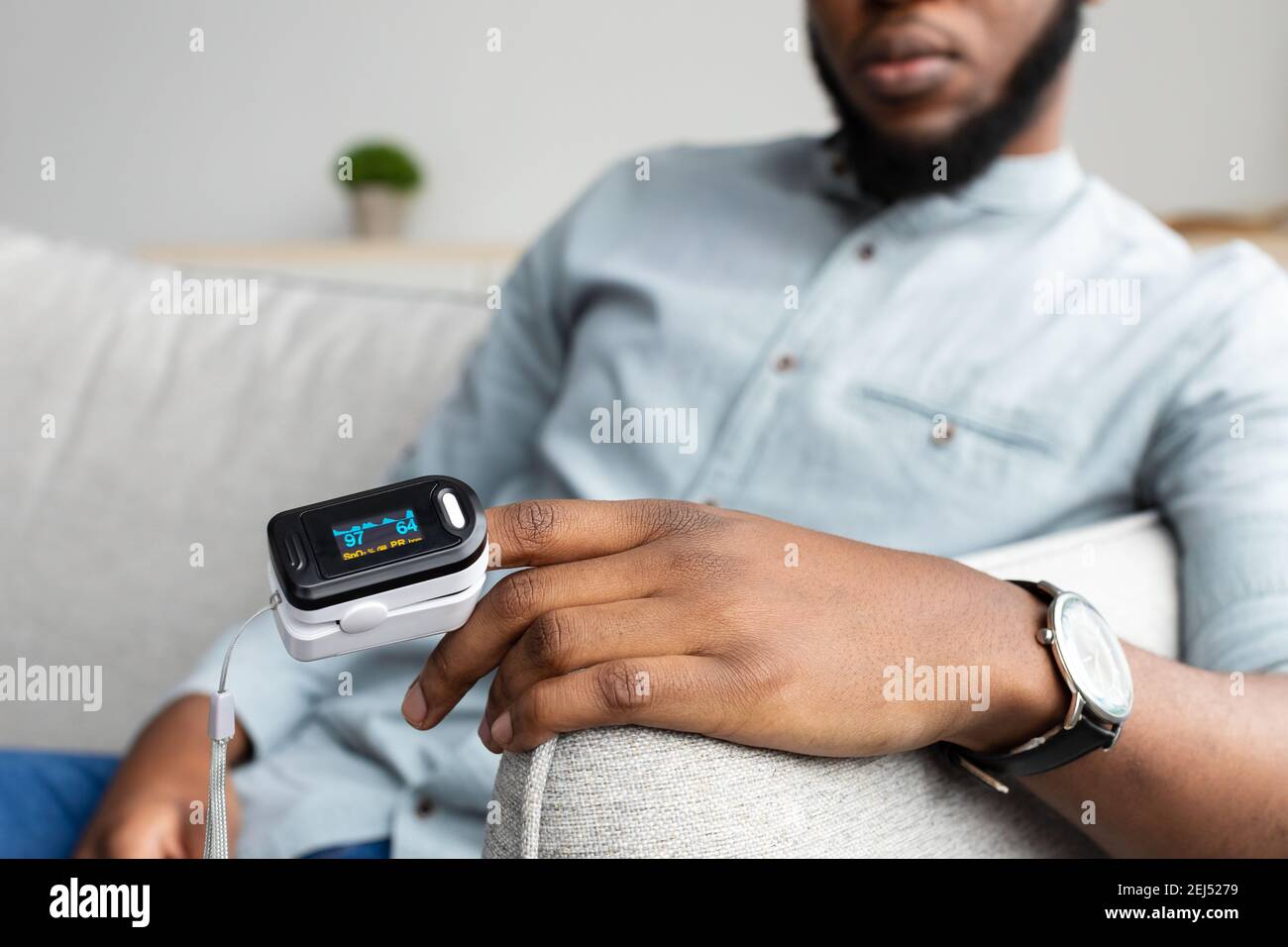 Black Man With Pulse Oximeter Measuring Oxygen Saturation At Home Stock Photo